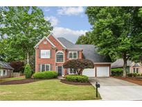 Charming two-story brick home with a well-manicured lawn and mature trees at 321 Woodbrook Crst, Canton, GA 30114