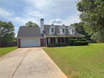 Charming brick home with a manicured lawn, dormer windows, and a long driveway at 1012 Gloria Grand Blvd, Mcdonough, GA 30252
