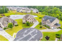An aerial view of neighborhood homes with a pond and fountain in a well-manicured cul-de-sac at 6390 Yellow Birch St, Cumming, GA 30040