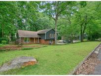 Charming home with a lush green yard, beautiful trees and stone and brick details at 588 Benson Hurst Sw Dr, Mableton, GA 30126
