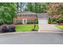 Charming two-story brick home featuring a manicured lawn, mature trees, and a two-car garage at 4507 Reva Way, Marietta, GA 30066