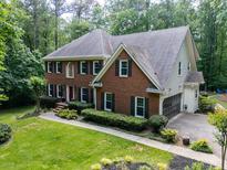 Charming brick home with lush landscaping, mature trees, and a two-car garage on a verdant lawn at 4673 Jefferson Township Pl, Marietta, GA 30066