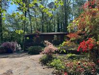 Charming home exterior with a colorful garden and a backdrop of lush green trees creating a serene and inviting curb appeal at 1053 Allgood Rd, Stone Mountain, GA 30083