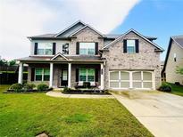 Charming two-story brick home with a well-manicured lawn and covered front porch perfect for relaxing at 2579 Wimberley Pine Ct, Dacula, GA 30019