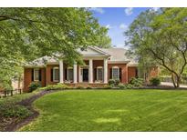 Charming brick home with a well-manicured lawn, lush landscaping, and classic colonial-style architecture at 3715 Borning Ct, Johns Creek, GA 30022