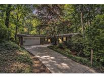 Charming ranch home featuring a well-manicured lawn, mature trees, and an attached two-car garage at 6590 Williamson Ne Dr, Atlanta, GA 30328