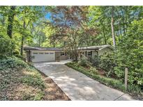 Charming home featuring a two-car garage and a long drive leading up to the house, nestled among lush greenery at 6590 Williamson Ne Dr, Atlanta, GA 30328