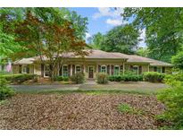 Charming brick home with a well-manicured lawn, mature trees, and welcoming front entrance at 11190 Hembree Springs Dr, Roswell, GA 30076