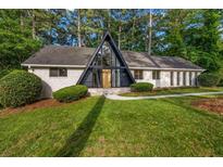 Stunning A-frame home with a well-manicured lawn, mature trees, and a brick facade at 4274 Smithsonia Ct, Tucker, GA 30084