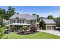 Beautiful brick home featuring a covered porch, manicured lawn, and three car garage at 4830 Westgate Dr, Cumming, GA 30040