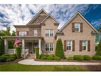 Charming brick two-story home with stone accents, shutters, manicured landscaping, and covered front porch at 3825 Valleyway Rd, Cumming, GA 30040