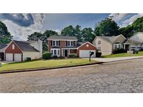 Charming two-story brick home with a manicured front lawn and attached two car garage at 4954 Penscot Way, Stone Mountain, GA 30088