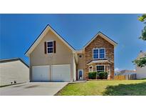 Charming two-story home features a stone facade, attached two-car garage, and well-maintained lawn at 5136 Estonian Dr, Fairburn, GA 30213