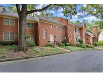 Beautiful red brick townhome with manicured landscaping and a charming front entrance with mature trees at 40 Ivy Chase Ne, Atlanta, GA 30342