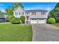 Charming split-level home featuring a two-car garage, gray siding, mature trees, and a well-manicured front yard at 4807 Willowwood Ne Dr, Kennesaw, GA 30144