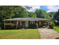 Charming brick home with a well-maintained lawn, carport, and an American flag displayed out front at 112 Hilltop Dr, Newborn, GA 30056