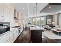 A modern, open-concept kitchen boasts white cabinets, stainless appliances, and a center island, seamlessly flowing into the living area at 58 Canton St # 404, Alpharetta, GA 30009