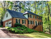 Charming two-story brick home with attached garage, surrounded by lush greenery and mature trees at 1461 Fox Forest Sw Ter, Lilburn, GA 30047