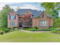 Beautiful two-story brick home featuring manicured landscaping and mature trees surrounding the property at 2118 Town Manor Ct, Dacula, GA 30019