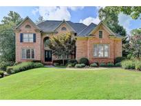 Elegant brick home featuring manicured lawn, mature trees, and a welcoming entrance at 2118 Town Manor Ct, Dacula, GA 30019