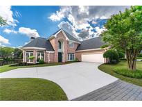Stately brick home with a circular driveway, lush lawn, mature landscaping, and a three-car garage at 9325 Saint Georgen Cmn, Duluth, GA 30097