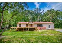 Ranch-style home featuring a red roof, brick foundation, and a wooden deck overlooking the grassy front yard at 428 Cornish Mountain Rd, Oxford, GA 30054
