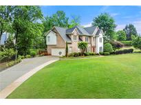 Stately brick home with a manicured lawn, circular driveway, and lush landscaping at 125 Forrest Lake Rd, Johns Creek, GA 30022