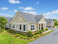 Inviting single-story home featuring manicured landscaping, neutral paint, dark shutters, and a charming brick accent at 306 Cherokee Station Cir, Woodstock, GA 30188