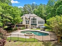 Backyard pool featuring a stone border, hot tub, and an elegant wrought iron fence at 8170 Hurakan Creek Xing, Cumming, GA 30028