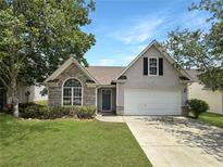 Charming home featuring stone accents, a well-manicured lawn, and a two-car garage at 2628 Downingwood Ln, Grayson, GA 30017