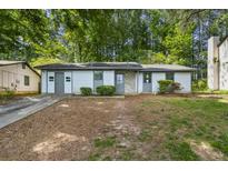 A single-story home with light siding, a stone accent, and a long driveway at 5445 Mallard Trl, Lithonia, GA 30058