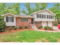 Charming brick home featuring black shutters, a well-manicured lawn, and a two-car garage at 5911 Christopher Ln, Lithonia, GA 30058
