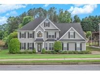 Charming two-story home with a well-manicured lawn, lush greenery, and traditional architectural details at 225 Ruby Forest Pkwy, Suwanee, GA 30024