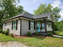 Charming home featuring a covered porch with a bright blue front door, complemented by black shutters and neutral siding at 6567 Post Rd, Douglasville, GA 30135