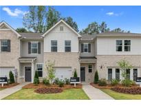 Charming townhomes featuring neutral brick, siding and trim, and professionally landscaped front yards at 320 Navigator Ln, Mcdonough, GA 30253