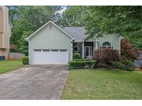 Charming home with a two-car garage and manicured landscaping, lush green lawn, and mature trees at 4047 Watkins Glen Dr, Woodstock, GA 30189