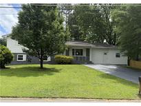 Charming single-story home with a lush green lawn and a paved driveway at 5460 Huron Dr, Morrow, GA 30260