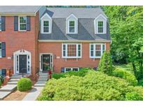 Charming red brick townhome featuring a well-maintained yard and classic architectural details at 701 Dunwoody Chace, Atlanta, GA 30328