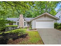 Charming home featuring a stone chimney, well-manicured lawn, and attached two-car garage at 413 Sassafras Rd, Roswell, GA 30076