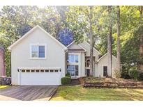 Two-story home featuring an attached garage and mature trees on a lush, green lawn at 5335 Lexington View Pl, Sugar Hill, GA 30518