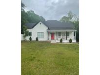 Attractive home featuring a classic front porch, neat landscaping, and a vibrant red door at 6860 Parkway Dr, Lithonia, GA 30058