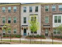 Charming townhome featuring a brick facade, black iron fence, and well-maintained landscaping at 808 Angora Aly, Scottdale, GA 30079