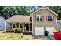 Charming two-story home featuring stone accents and red shutters, complemented by a two-car garage at 4827 Wyndam Dr, Stone Mountain, GA 30088