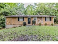 Charming single story home featuring a well-kept lawn, trimmed shrubs, and a unique stone facade at 5509 Covent Way, Lithonia, GA 30058