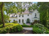 Elegant white home featuring manicured landscaping, complemented by lush greenery and a striking arched entryway at 341 Lands Se Ml, Marietta, GA 30067