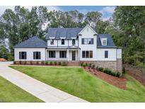 Beautiful white two-story home with a manicured lawn, black shutters, and a brick foundation at 7620 Breeze Bay Rd, Cumming, GA 30041
