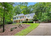 Traditional two-story home featuring a brick facade, well-manicured lawn, and lush landscaping at 525 Watergate Ct, Roswell, GA 30076