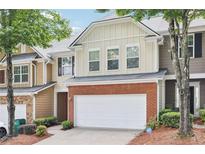 Charming townhome featuring a brick facade and attached two-car garage at 607 Tall Timbers, Woodstock, GA 30188
