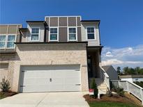 Modern two-story townhome featuring a brick facade, two-car garage, and well-maintained landscaping at 2335 Portrush Way (Lot 26) Dr, Atlanta, GA 30339