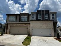 Modern townhomes featuring light brick, neutral siding, two car garages and contemporary architectural details at 2335 Portrush Way (Lot 26) Dr, Atlanta, GA 30339